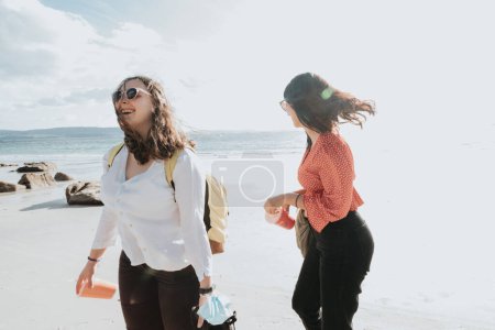 Photo for Happy young women laughing and smiling at the beach on a summer day, enjoying vacation, concept of friendship enjoying the outdoor - Royalty Free Image