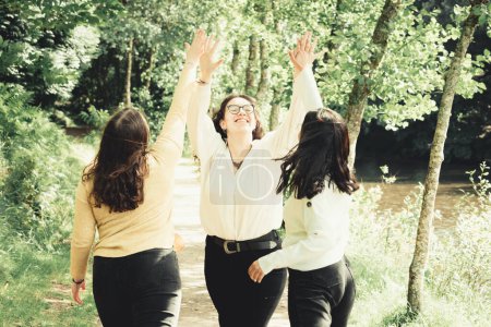 Foto de "3 mujeres jóvenes riendo y aplaudiendo juntas en el bosque, concepto de amistad y cuidado" - Imagen libre de derechos