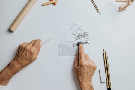 Photo for "High angle view of a senior Caucasian woman drawing sketches in studio. Creativity, education and people concept,cognitive functions clock drawing self assessment test at home with positive results" - Royalty Free Image
