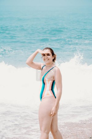 Photo for "Young woman in a swimsuit in front of the ocean turning around to camera and smiling, copy space, liberty and future concept" - Royalty Free Image
