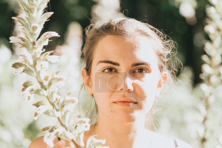Photo for "Close up portrait of a serious young woman near some flowers, mental health and self care concepts, psychology, young" - Royalty Free Image
