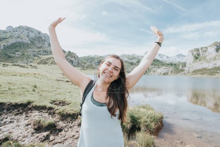 Photo for Portrait of young smiling woman face partially covered with flying hair in windy day standing at mountain - carefree woman - Royalty Free Image
