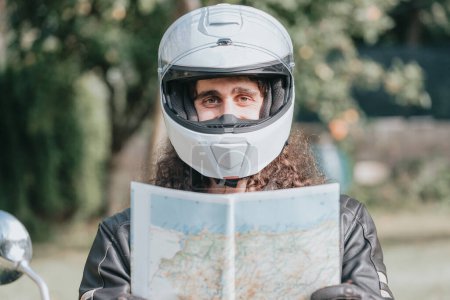 Foto de Motorbike travel holding a map while smiling to camera while using a helmet. Travel in bike concept. Long hair man happy digital nomad concepts. - Imagen libre de derechos