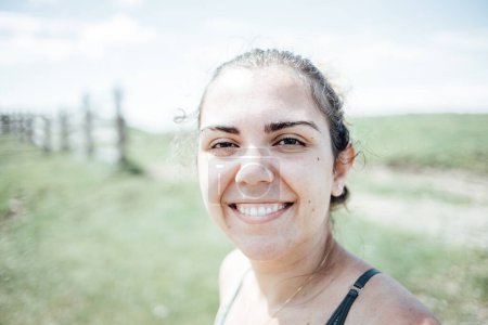 Foto de "Retrato de una joven sonriendo directamente a la cámara después de una sesión de senderismo en las montañas" - Imagen libre de derechos