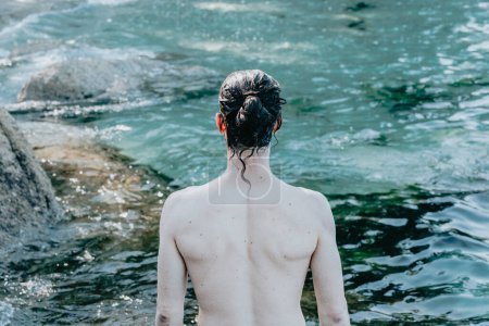 Photo for The back of a young man in front of the ocean during a sunny day with confidence, liberty and future concepts, copy space, summer, holiday - Royalty Free Image