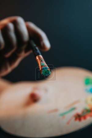 Foto de Hands of old female artist holding messy dirty paint brushes with different paints in art studio. Lifestyle and hobby concept - Imagen libre de derechos