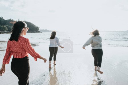 Photo for Happy women friends runs at sea beach during a bright day, friends happy relax having fun playing on beach near sea when sunset in evening. - Royalty Free Image