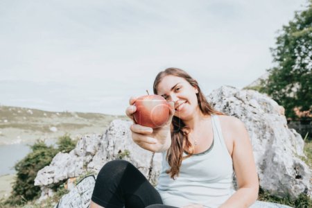 Foto de Hiker having a snack eat apple in the mountains, long trail rest, hiking activity, leisure and nature sport. Resting during the route in the lakes. Healthy life style with copy space for text - Imagen libre de derechos