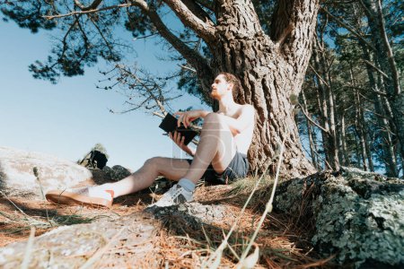 Téléchargez les photos : Jeune hippie homme lisant un livre, plan grand angle, réseau social, ambiance estivale style de vie détendu - en image libre de droit