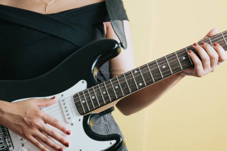 Téléchargez les photos : "Gros plan d'une jeune femme jouant de la guitare à l'extérieur. Journée ensoleillée et pratique d'un concept d'instrument. Copier espace musique vie en tournée et la nature." - en image libre de droit