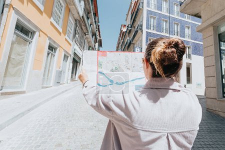 Téléchargez les photos : Jeune femme indépendante utilisant une carte au milieu d'une rue en Europe, journée ensoleillée, journée d'été, concepts de voyage, nouveaux horizons, espace de copie - en image libre de droit