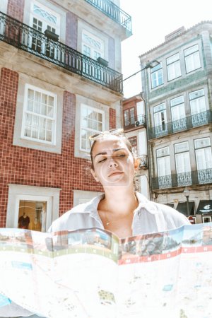 Foto de "Joven turista buscando un mapa en medio de una calle dudando de qué hacer, día de verano, soleado, porto, ciudad mediterránea," - Imagen libre de derechos