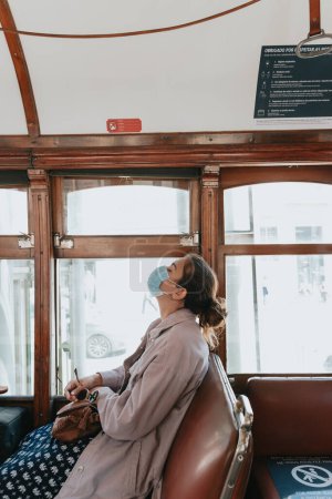 Foto de Mujer en un tren mirando hacia arriba mientras usa una máscara, desesperación y concepto de estrés por virus - Imagen libre de derechos