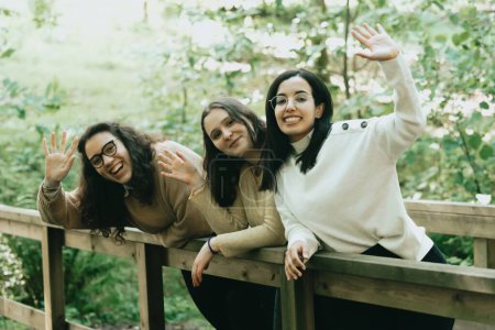 Téléchargez les photos : "Trois jeunes femmes saluant la caméra effusivement tout en souriant, concept d'amitié et de bonheur" - en image libre de droit