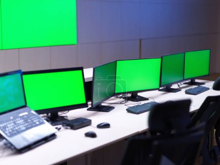 Foto de Interior of big modern security system control room with blank green screens - Imagen libre de derechos