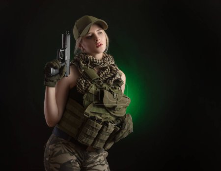 Foto de Chica en ropa militar especial posando con una pistola en sus manos sobre un fondo oscuro en la niebla - Imagen libre de derechos
