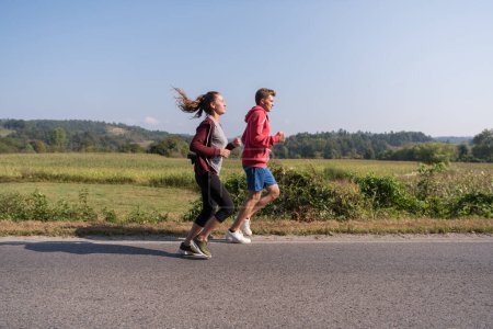 Foto de "pareja joven trotando a lo largo de un camino rural" - Imagen libre de derechos