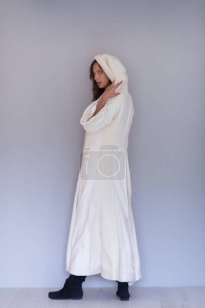 Téléchargez les photos : "femme en manteau blanc avec capuche sur fond gris" - en image libre de droit