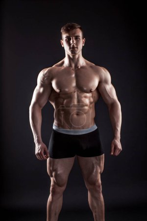 Téléchargez les photos : "Musclé bodybuilder gars faisant posant sur fond noir
" - en image libre de droit