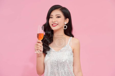 Foto de Chica asiática de buen aspecto en elegante atuendo de pie en pose de confianza con vid sobre fondo rosa. - Imagen libre de derechos