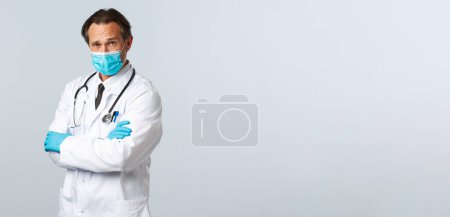 Téléchargez les photos : "Covid-19, prévention du virus, personnel de santé et concept de vaccination. Médecin professionnel confiant prenant soin des patients pendant une pandémie de coronavirus, poitrine croisée, porter un masque médical et des gants" - en image libre de droit
