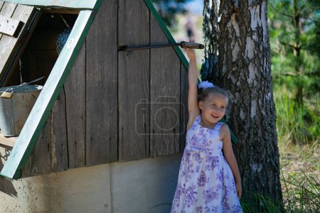 Photo for Surprised pretty little girl in country style staying near to well. - Royalty Free Image