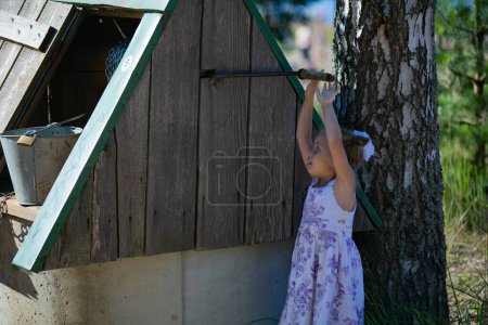 Photo for Surprised pretty little girl in country style staying near to well. - Royalty Free Image