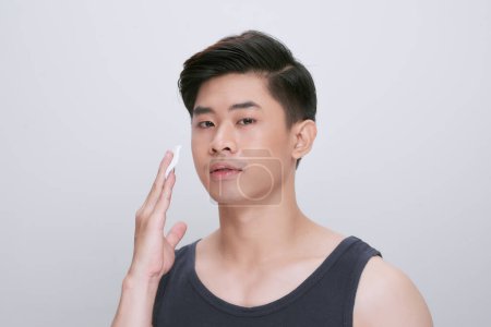 Photo for Man cleaning face skin with batting cotton pads over white background - Royalty Free Image