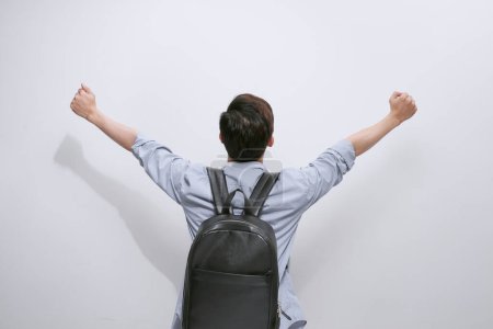 Téléchargez les photos : Vue arrière d'un homme décontracté célébrant le succès avec les mains en l'air sur fond blanc - en image libre de droit
