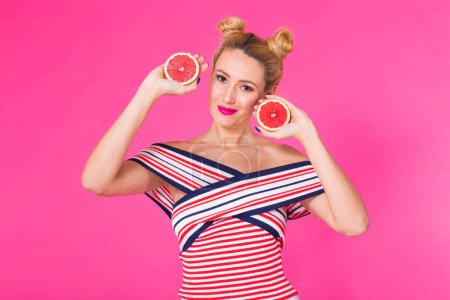 Photo for Smiling girl with grapefruit cut in half fruit in hand on pink background - Royalty Free Image
