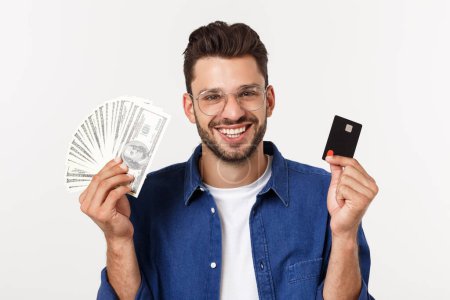Foto de Retrato de un hombre con barba frinada que tiene tarjeta de crédito y muestra dinero en efectivo aislado sobre fondo blanco - Imagen libre de derechos