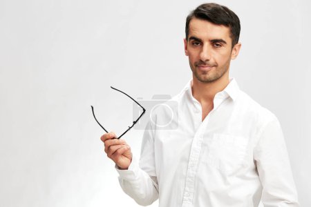 Foto de Exitoso hombre blanco camisa posando mano gesto gafas aislado fondo - Imagen libre de derechos