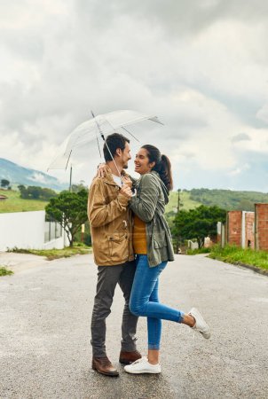 Photo for Its always a lovely day when Im with you. Cropped shot of a loving couple standing outside with an umbrella. - Royalty Free Image