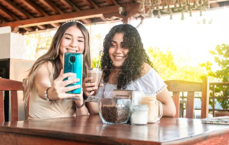 Téléchargez les photos : "Deux filles prenant un selfie et buvant du café, deux amies dans un café prenant un selfie" - en image libre de droit