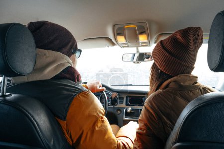 Téléchargez les photos : Couple familial assis en voiture en vêtements d'hiver dans la forêt de neige - en image libre de droit