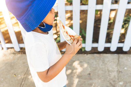 Photo for "Latin boy enjoying the summer and eating pizza dressed in comfortable clothes" - Royalty Free Image