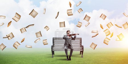 Photo for "Handsome businessman in park on wooden bench play his melody" - Royalty Free Image