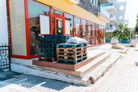 Foto de "Empty pallets outside the store. Wooden pallets on a hydraulic trolley. Warehousing equipment. Sold out commodities during panic buy. Goods deficit and shortage due to economic crisis" - Imagen libre de derechos
