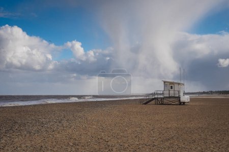 Téléchargez les photos : "Tempête de grêle au-dessus d'une cabane de sauveteur sur une plage froide et vide, Gorleston-on-Sea, Norfolk" - en image libre de droit