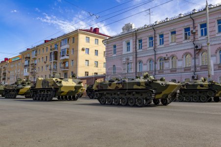 Photo for "Russian military vehicles on the city street against the backdrop of residential buildings. Russian modern military tank, infantry fighting vehicle BMP and armored personnel carrier BTR." - Royalty Free Image