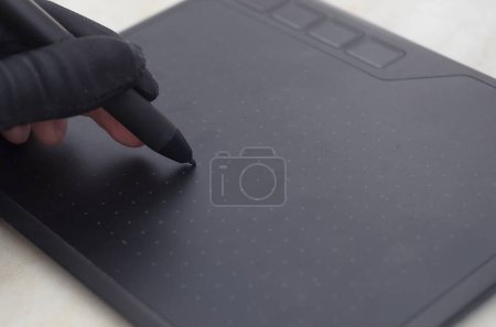 Photo for Graphic designer's hand in a black glove draws on the workspace of a graphics tablet - Royalty Free Image