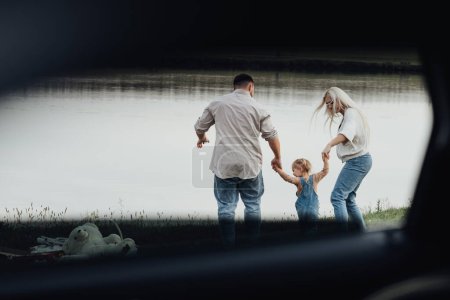 Foto de Familia joven feliz con el niño sosteniendo por las manos juntas y disfrutando de fin de semana fuera de la ciudad, Vista a través de la ventana dentro del coche - Imagen libre de derechos