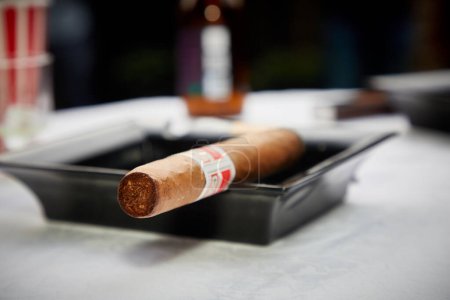 Photo for "Lit cigar in a black ashtray" - Royalty Free Image