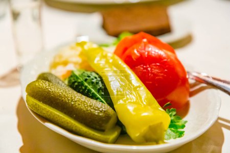 Photo for "Traditional Russian snacks (pickles, tomatoes, sauerkraut) are on the plate." - Royalty Free Image