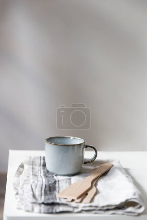 Foto de Two white mugs, a kitchen towel, a napkin and wooden frying utensils on the table. Defocus. - Imagen libre de derechos