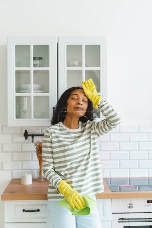 Foto de "Afroamericana sensación de alivio femenino después de terminar de limpiar la cocina. Cansado de las tareas domésticas" - Imagen libre de derechos