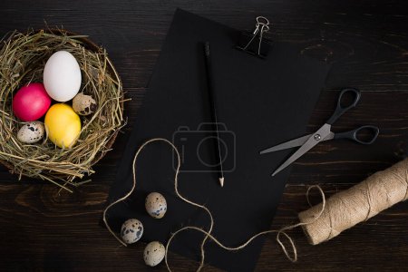 Foto de Huevos de Pascua en nido, tijeras e hilo sobre fondo negro - Imagen libre de derechos