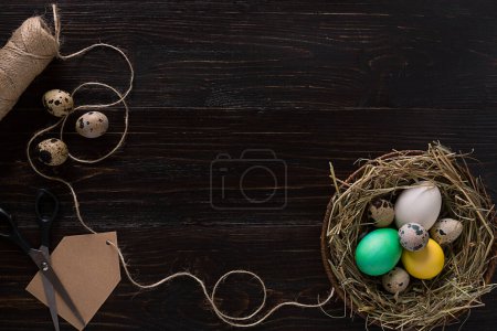Foto de "Coloridos huevos de Pascua en el nido en tablero de madera oscura." - Imagen libre de derechos