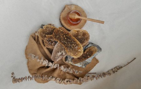 Photo for "Delicious honey dripping from Fresh honeycombs on Glass jar with Wooden honey dipper stick on sackcloth. " - Royalty Free Image