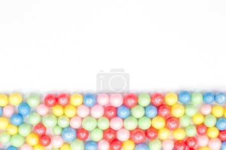 Foto de "Bolas brillantes redondas multicolores de la cubierta de la confitería de azúcar se encuentran en la parte inferior sobre un fondo blanco." - Imagen libre de derechos